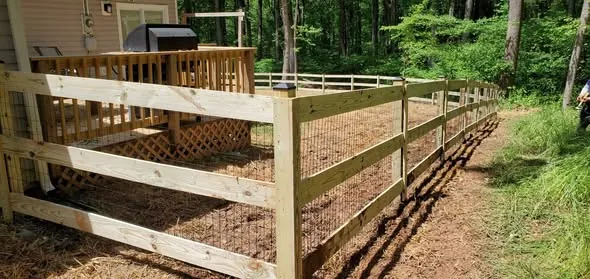 Split rail fence backed with wire mesh running along a wooded property line