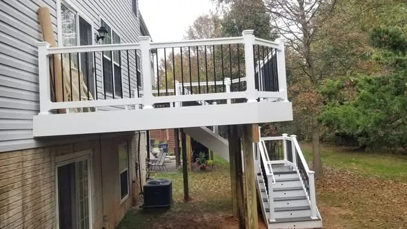 Elevated composite deck with white railing and a stair down to the yard