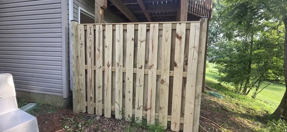 Pressure-treated board-on-board privacy fence built under a raised deck